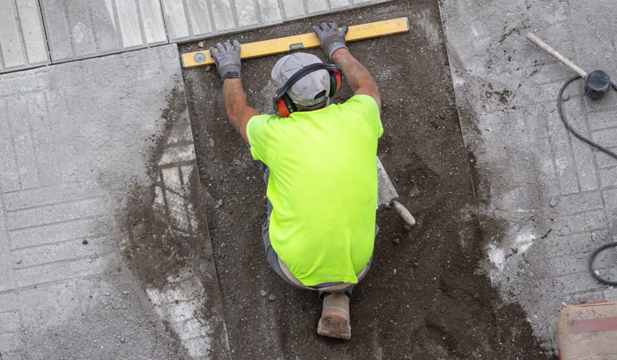 Construction worker with construction level working on a sidewalk. Maintenance concept