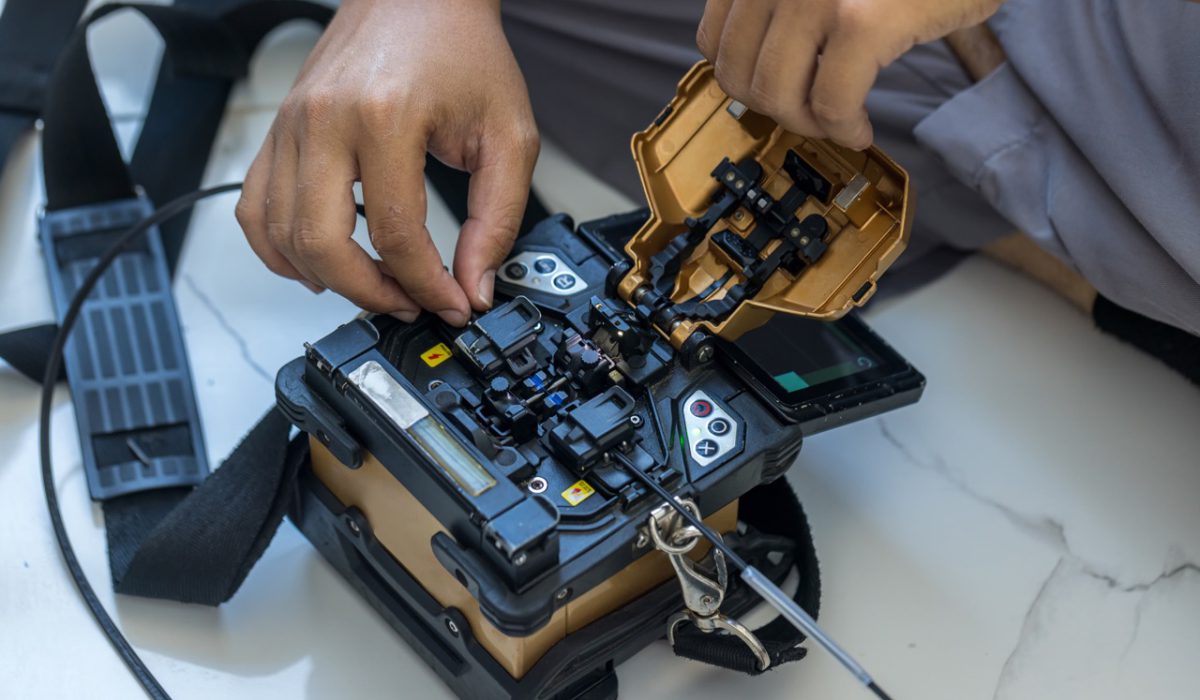 Optical fiber installation with Digital Fiber Optical Fusion Splicing machine. High precision fiber optic cleaver is being used during a fiber optic wire install at House.  Welding of optical fibers.